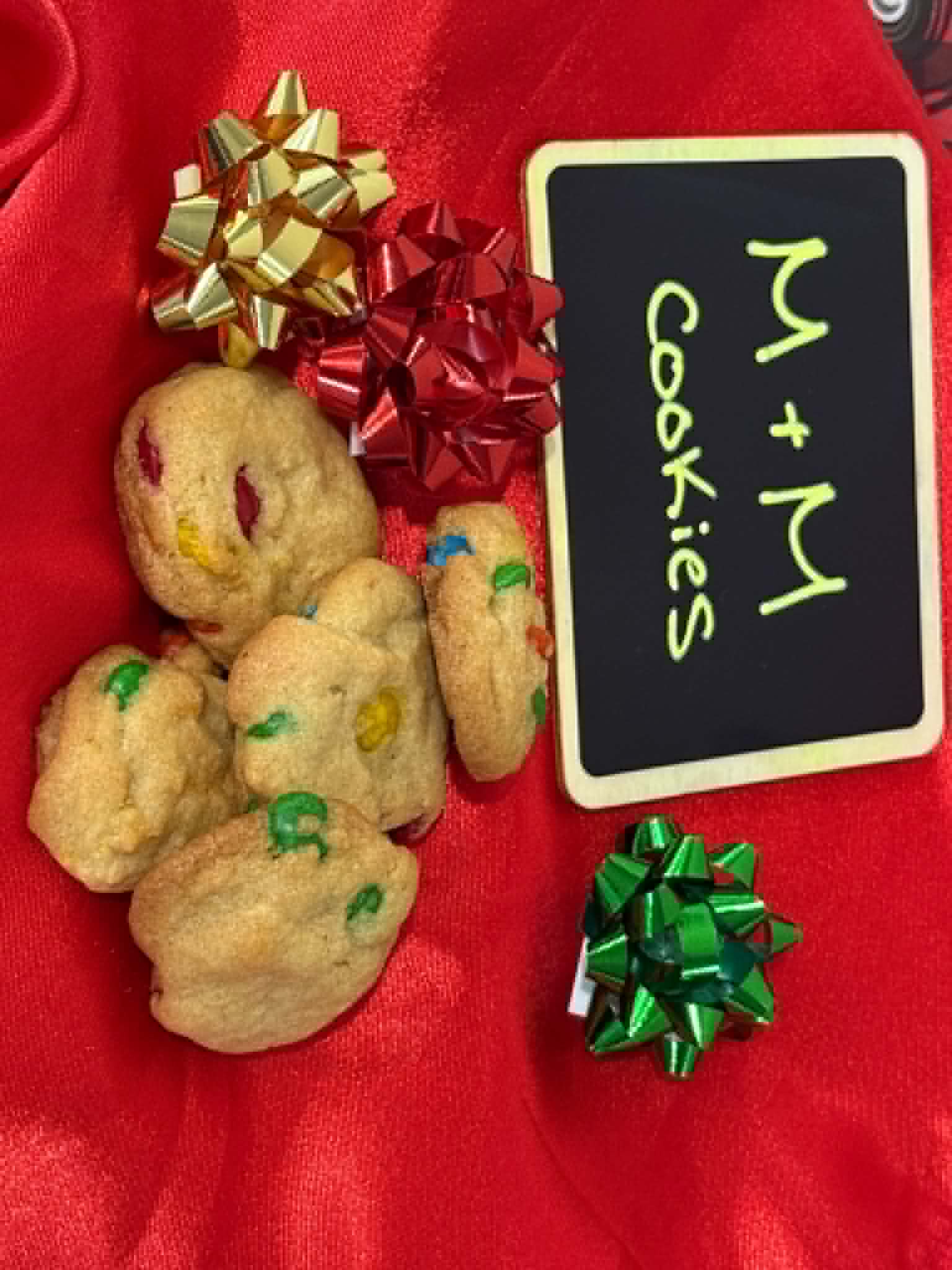 Soft M&M cookies on a red holiday backdrop with gift bows